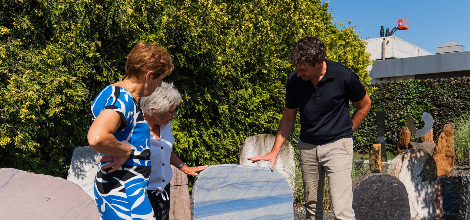 Adviseur toont een lichte natuurstenen grafsteen aan klanten